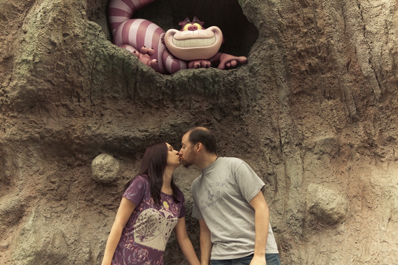 Couple kissing below Cheshire Cat statue