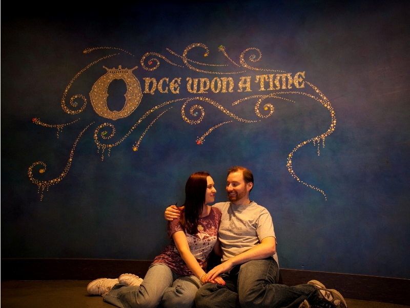 Couple sitting below mural that reads "once upon a time"