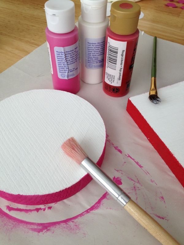 Art supplies, wood block and pink and red paint bottles