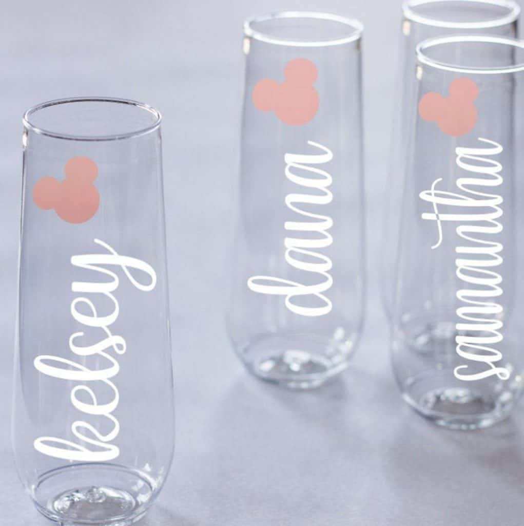 Three champagne flutes decorated with script font and a pink Mickey Mouse shaped decal