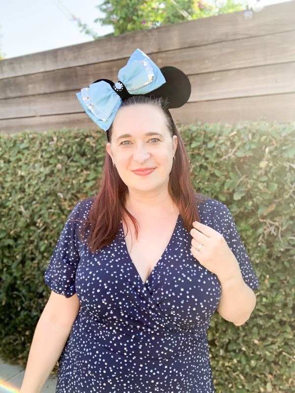 Woman wearing blue polka dot dress and Minnie Mouse ear headband