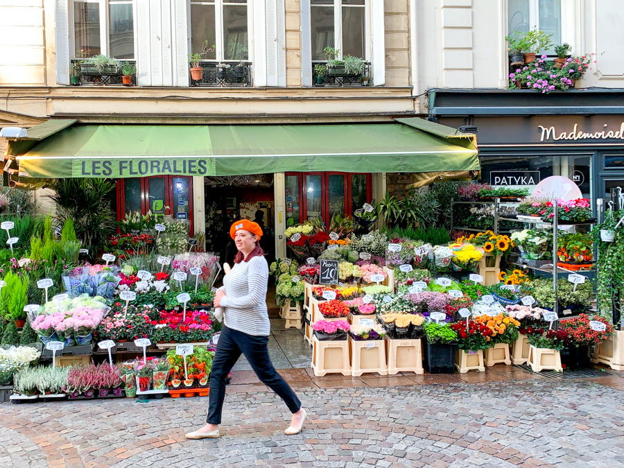 Woman walking in front of flower shop in Paris France