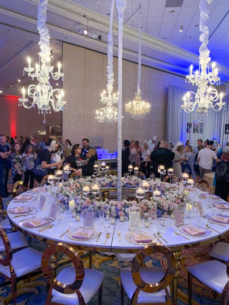 Circular white wedding reception table with gold chairs