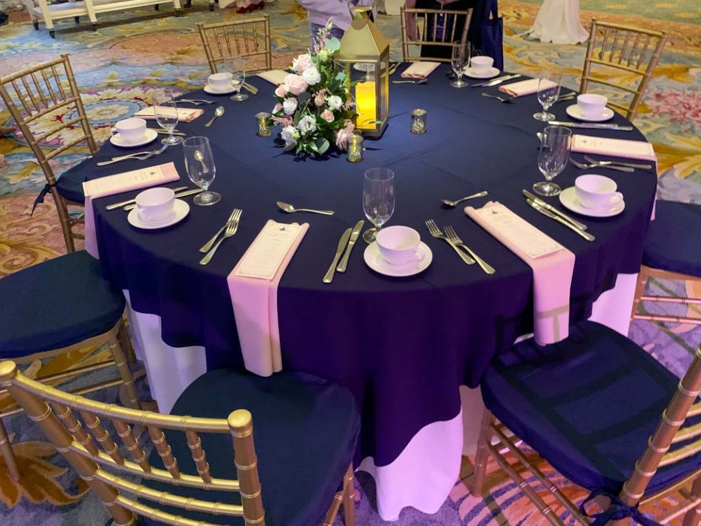 Wedding reception table with navy blue tablecloth and white napkins