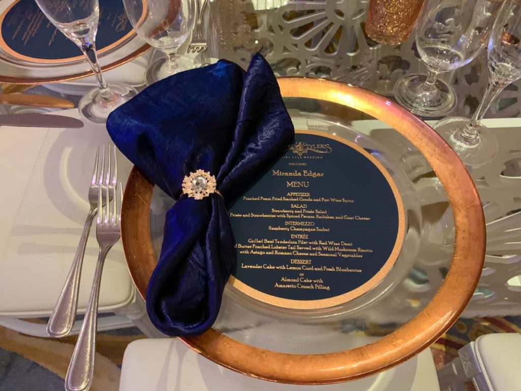 Close up of reception table with gold charger and navy blue folded napkin