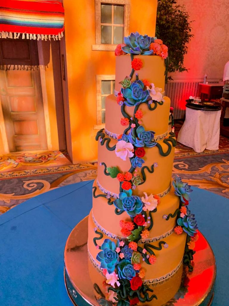 Colorful five tier wedding cake with yellow fondant and blue and red roses made of icing