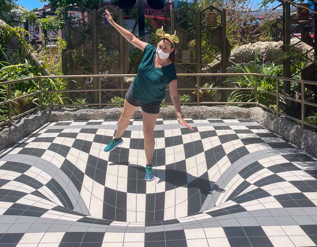 Woman posing with optical illusion floor at Avengers Campus