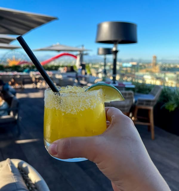 Hand holding mango margarita on the rooftop bar RISE at Westin Anaheim