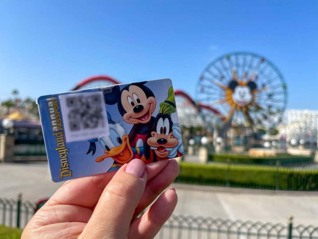 Hand holding up a Disneyland Annual Pass card with photopass code taped to it