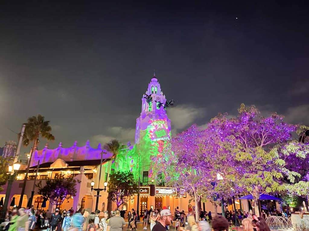 Carthay Circle Restaurant bell tower lit up in green and purple during Oogie Boogie Bash