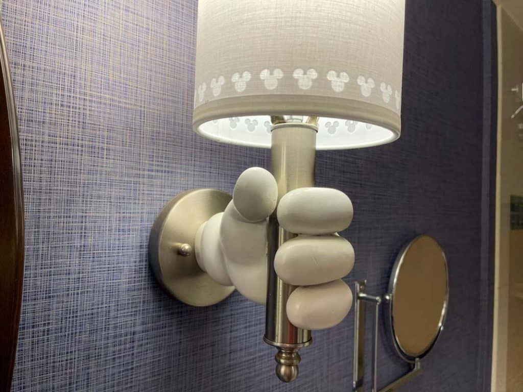 Close up of wall lamp at Disneyland Hotel room. It is shaped like Mickey's white glove holding a small lamp with white shade