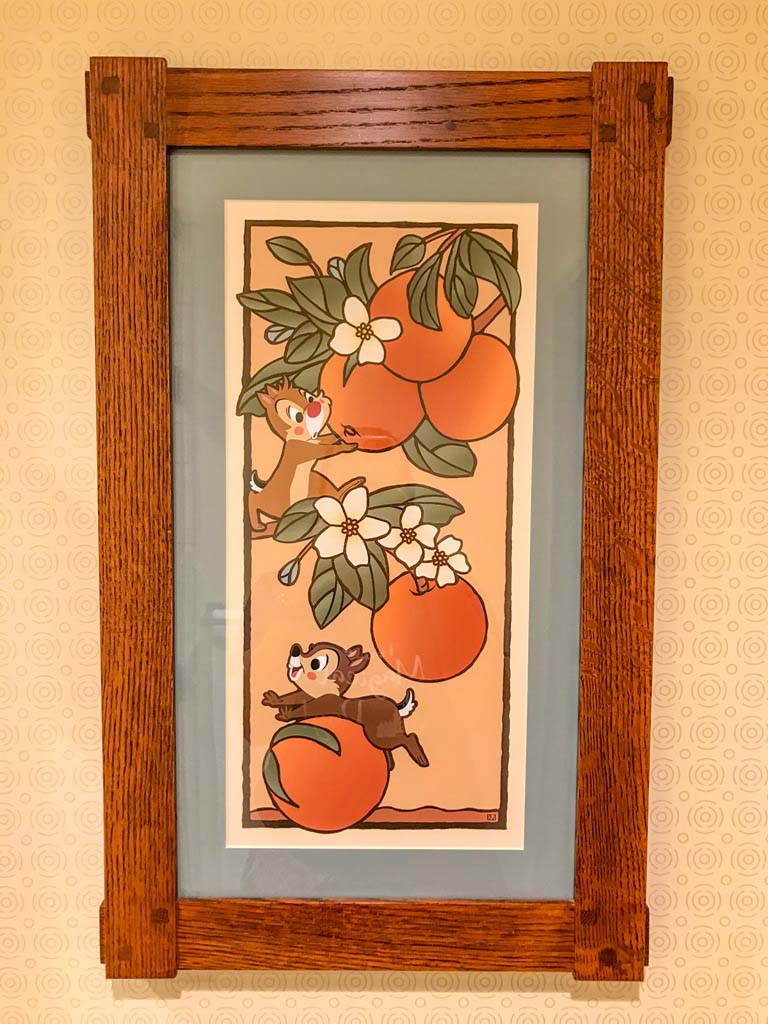 Vertical art of oranges hanging from a tree branch. Disney's Chip and Dale are playing on the branch.