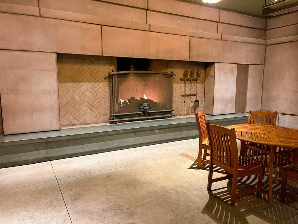 Ourdoor patio with brown table and chairs and large fireplace built into the wall