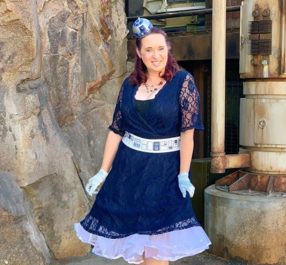 Woman wearing blue lace dress with R2D2 headband and belt