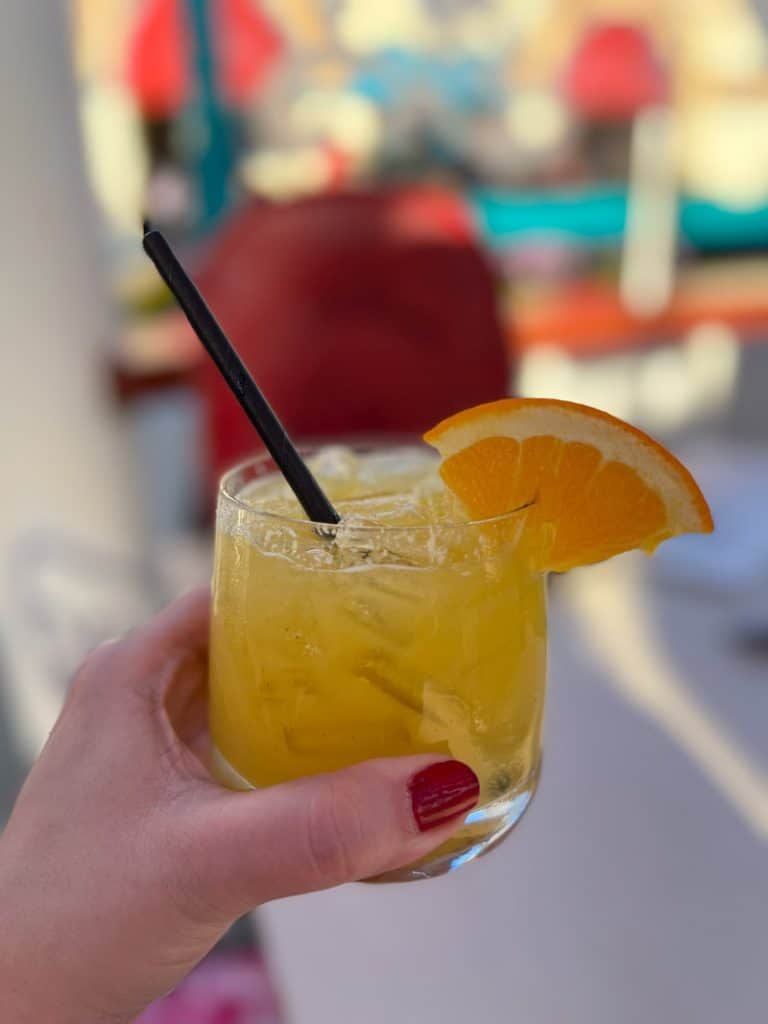 Yellow cocktail with orange wedge and black straw