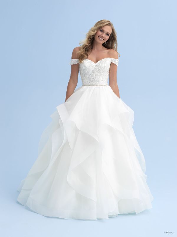 Woman wears white ballgown wedding dress in front of blue background