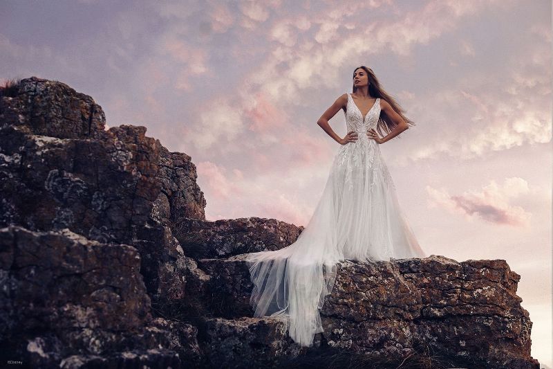 Bride stands against sunset wearing a beautiful wedding gown