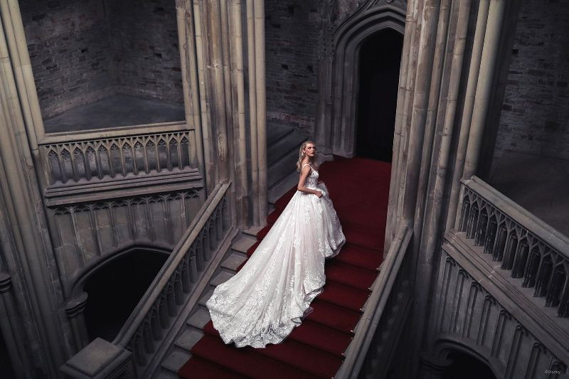 Bride wears wedding gown with long train, running up stairs