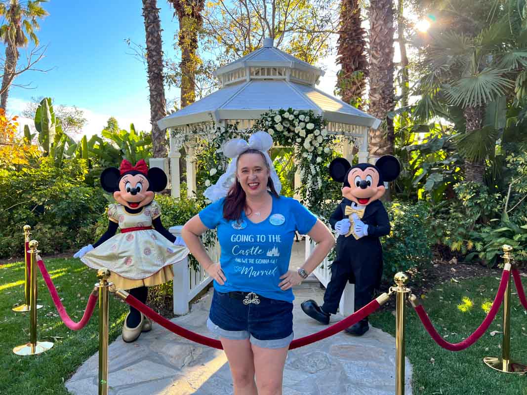 Woman in blue shirt poses with Minnie and Mickey Mouse at Disneyland Hotel