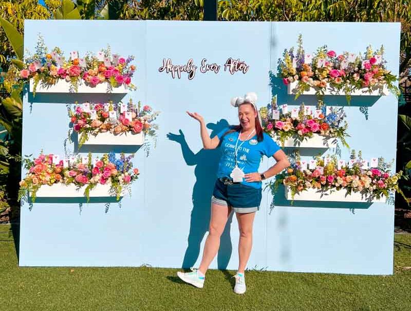Woman poses in front of sign that reads "Happily Ever After"