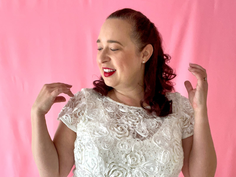 Close up of woman wearing white short sleeve dress with rosette pattern