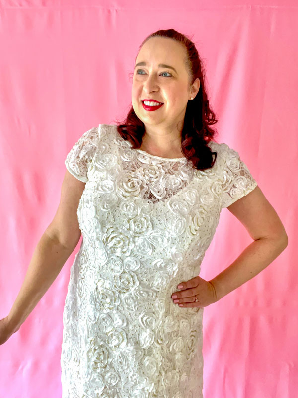 Woman wears white short sleeve dress with rosette pattern