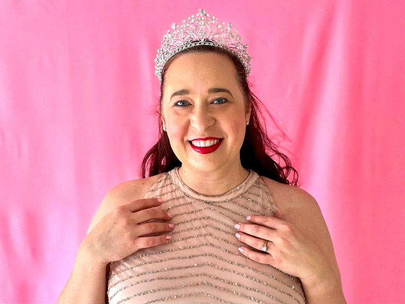 Close up of Woman wearing beige form fitting gown with silver beading and a silver tiara