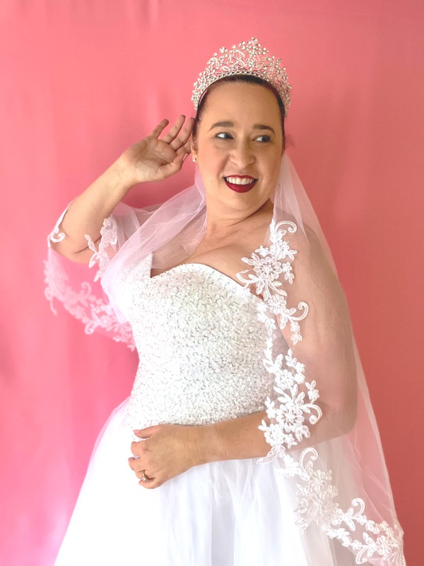 Bride wears white ballgown; she is holding out the tulle skirt and smiling