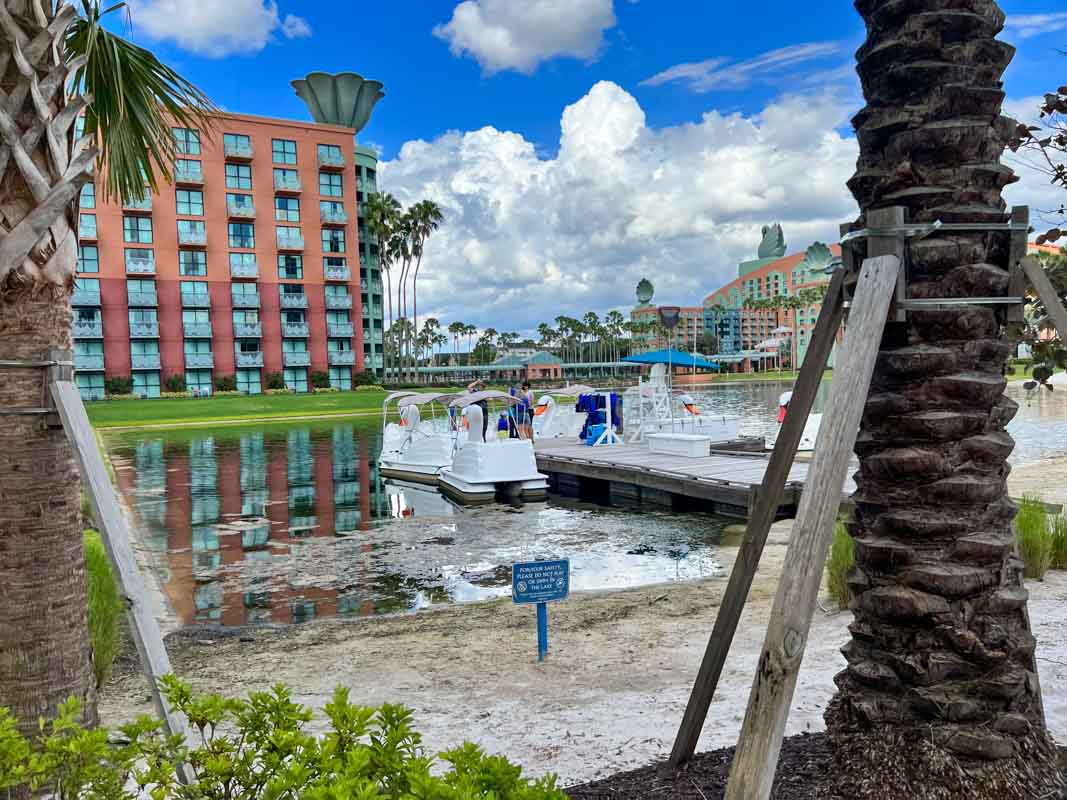 Swan boats sit by the dock on Crescent Lake with Swan and Dolphin building in the background