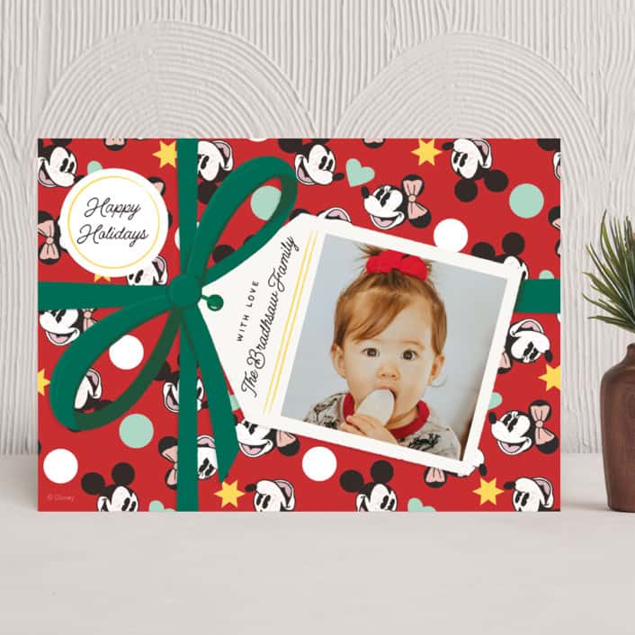 Holiday card with design that looks like a present with red Disney gift wrap