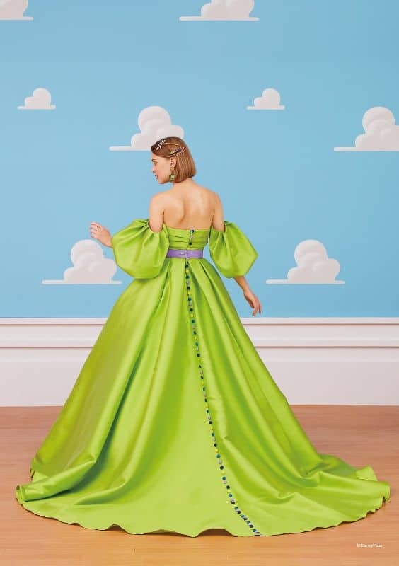 Woman wears light green ballgown with puffy sleeves and blue buttons down the back