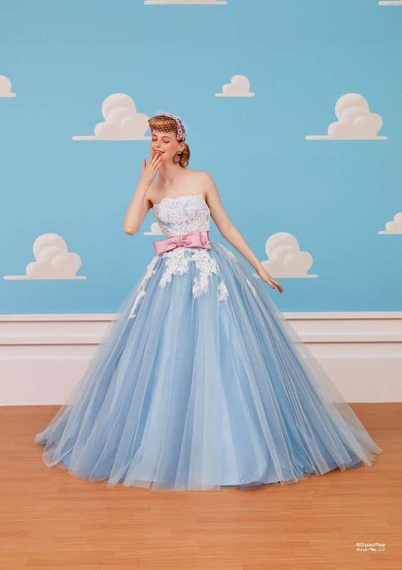 Woman wears light blue ballgown with pink sash at the waist.