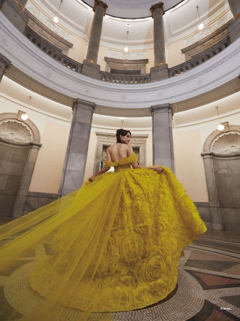 Woman seen from the back, wearing bright yellow ballgown with rosette design on the skirt, inspired by Belle