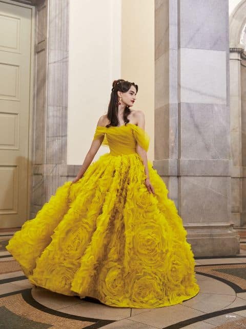 Woman wearing bright yellow ballgown with rosette design on the skirt, inspired by Belle