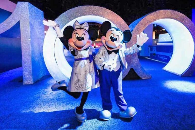 Mickey and Minnie pose in front of a "100" sign at D23 Expo