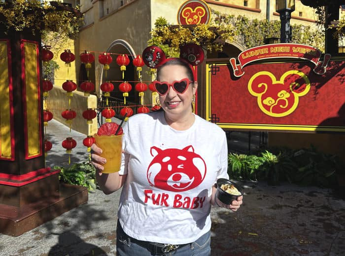 Woman poses with food and drink at Lunar New Year festival at Disney California Adventure