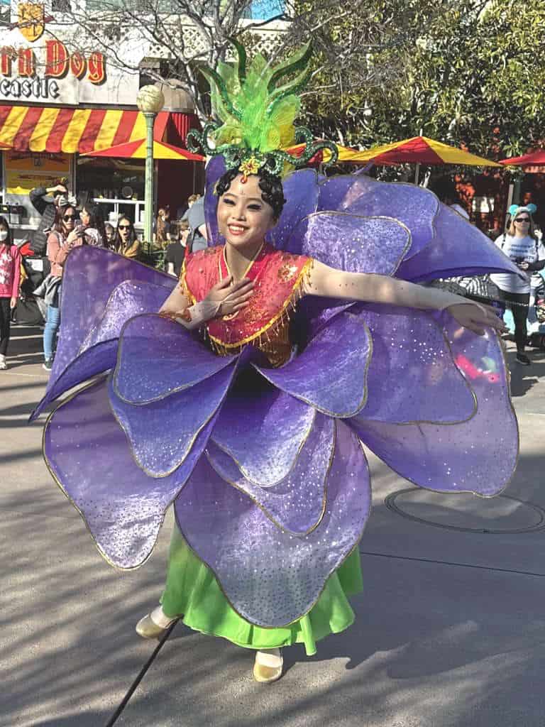 A woman poses in a flower dress during the Lunar New Year processional at Disney California Adventure