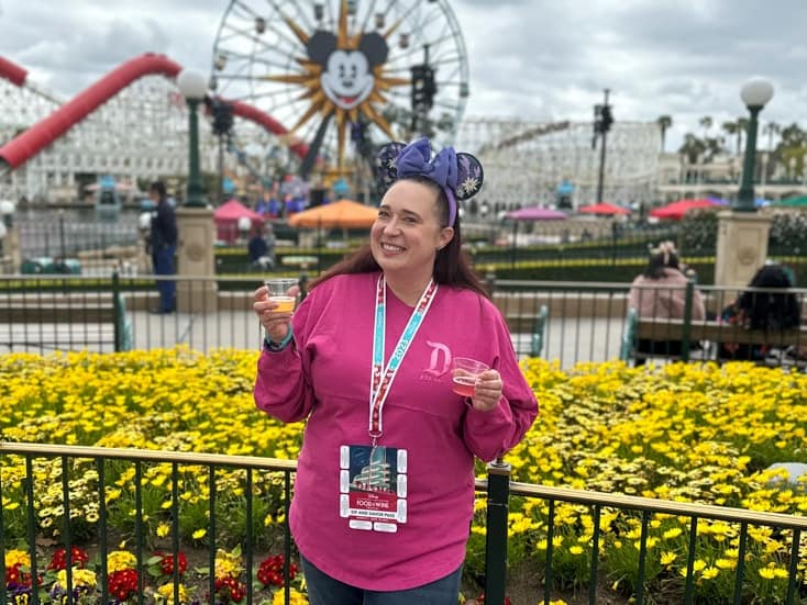 Woman poses holding two glasses of wine at Disney California Adventure Food and Wine