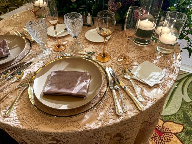 Close up of wedding reception table showing sequin table cloth and white plate on top of gold charger