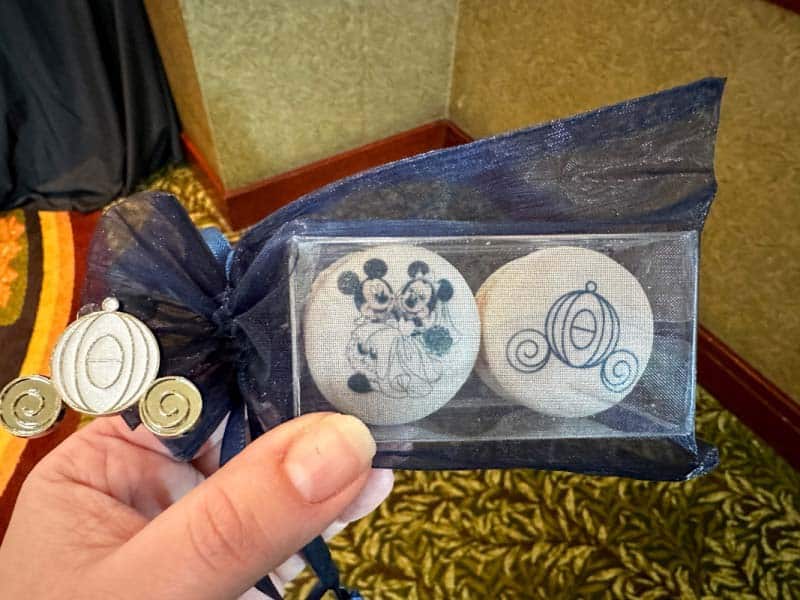 Two white macrons with Disney wedding images on them, inside a blue organza bag