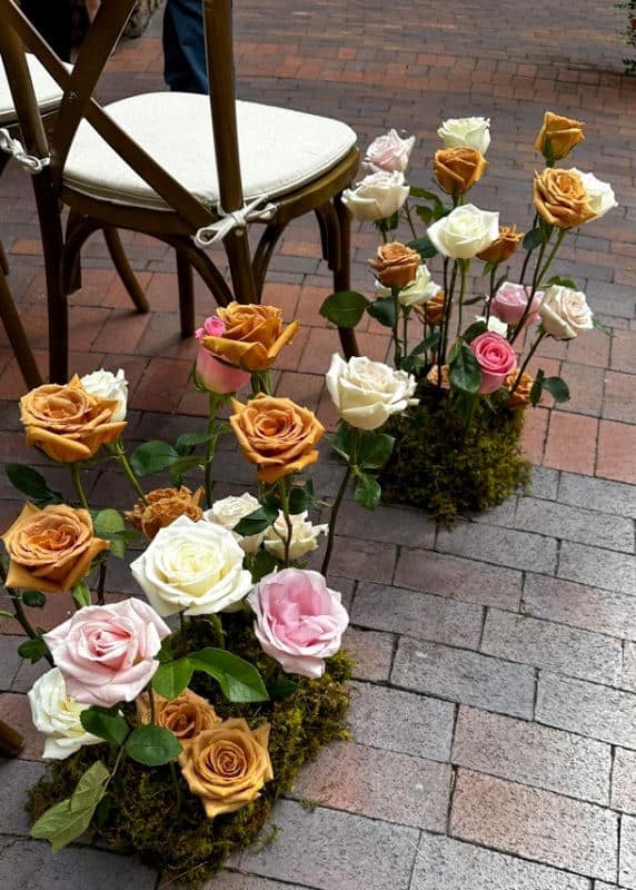 Floral arrangements with light pink, white, and caramel colored long stem roses arranged in a moss covered dome