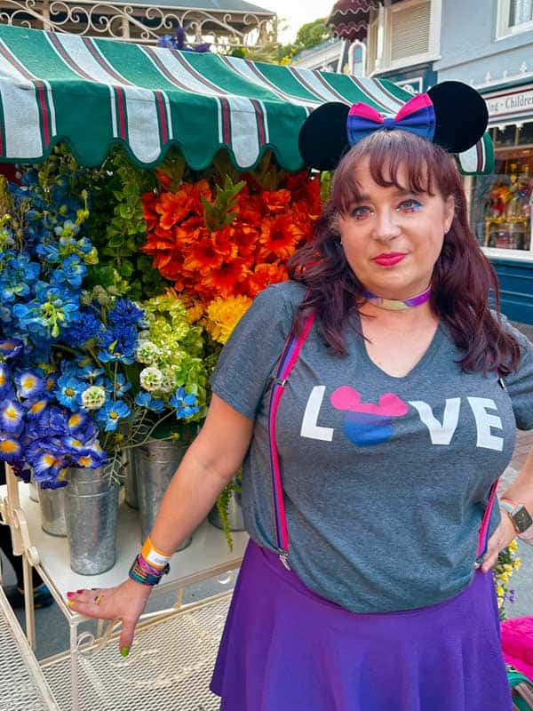 a woman standing in front of a flower stand at Disneyland