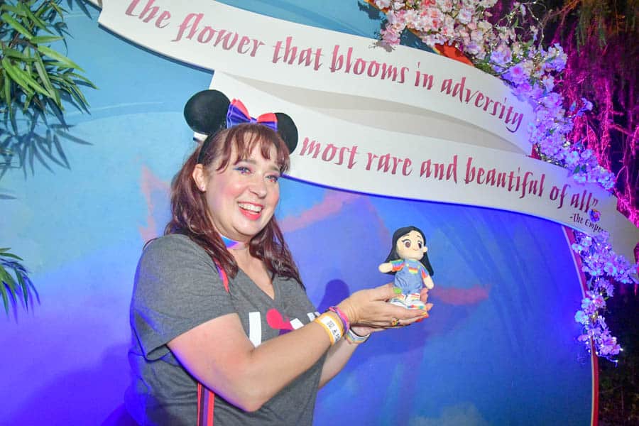 Woman poses with Mulan themed backdrop at Disneyland Pride Nite