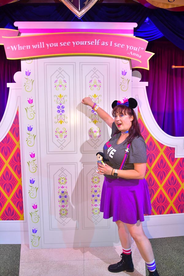 Woman poses with Frozen themed backdrop at Disneyland Pride Nite