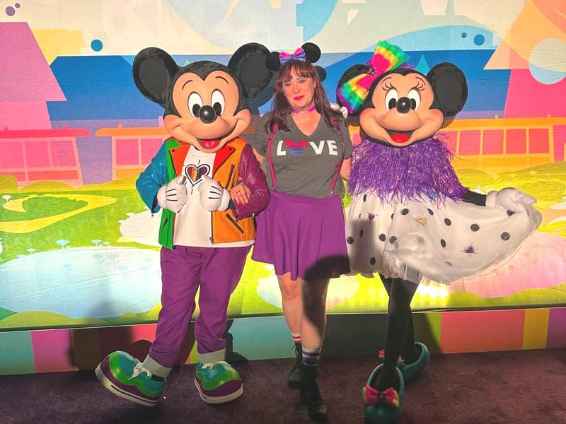 Woman poses with Mickey and Minnie at Disneyland Pride Nite