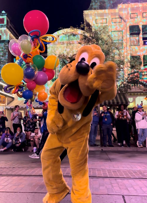 Pluto waves along the parade route on Disneyland Pride Nite