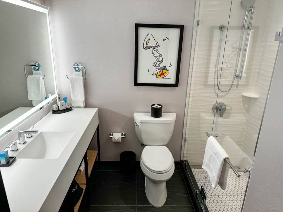 Pixar Place Hotel standard room bathroom equipped with a sink, toilet and a shower.