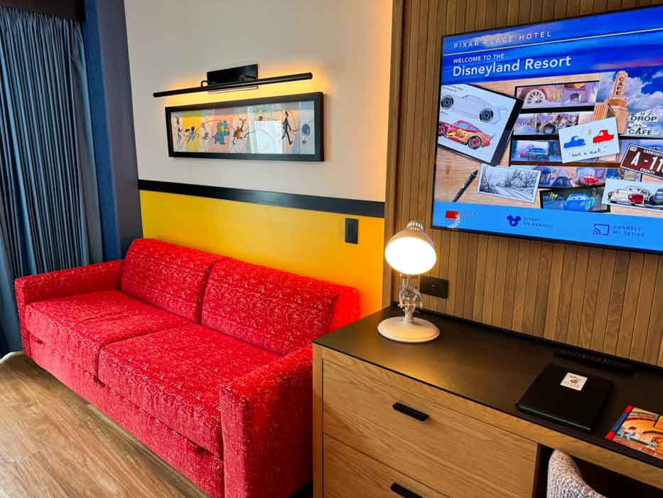 The Pixar Place Hotel standard hotel room boasts a flat panel tv and a red couch that converts into a bed