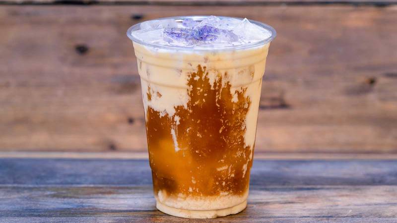 A refreshing iced coffee adorned with delicate lavender flowers, one of the enticing new Disneyland food items for 2024.