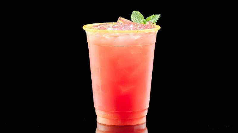 A pink drink with a mint garnish on a black background.